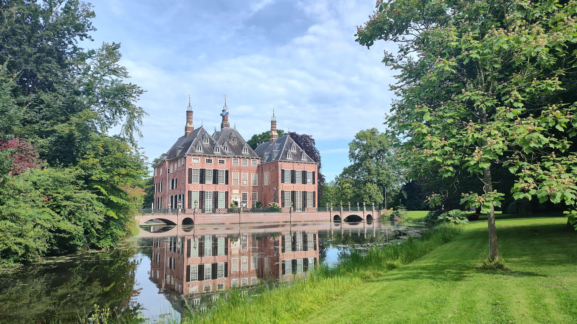 Kasteel Duivenvoorde weerspiegeld in de slotgracht, omringd door groen